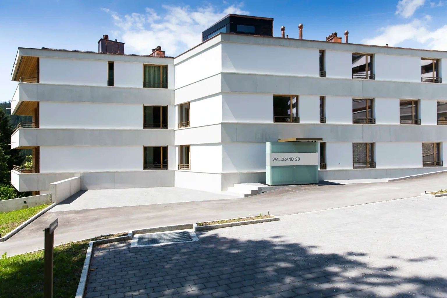 MFH Haus am Waldrand Flims Waldhaus Fassade Hauseingang an der Strasse