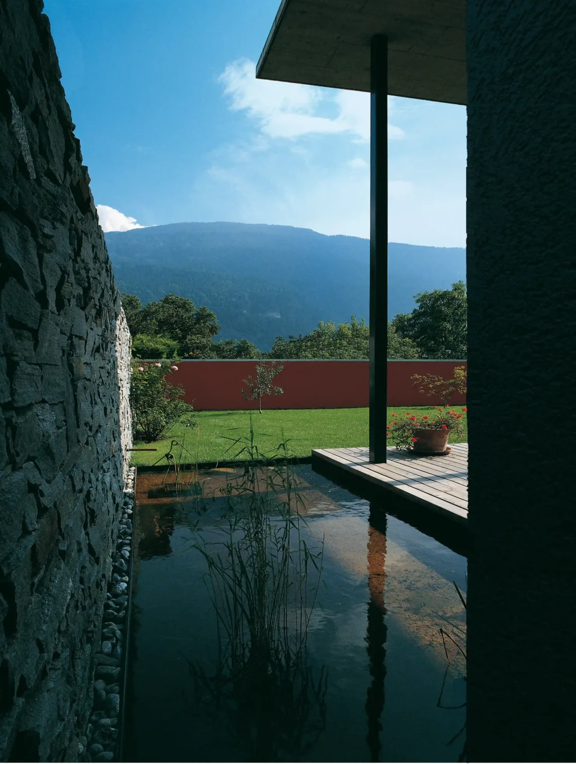 Wohnhaus Cavigelli DomatEms Garten mit Natursteinemauer, Teich und Wiese